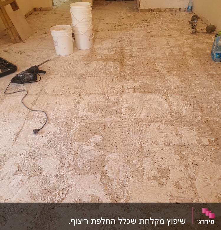 רצפה מפורקת עם דליים וכלי עבודה לשיפוץ